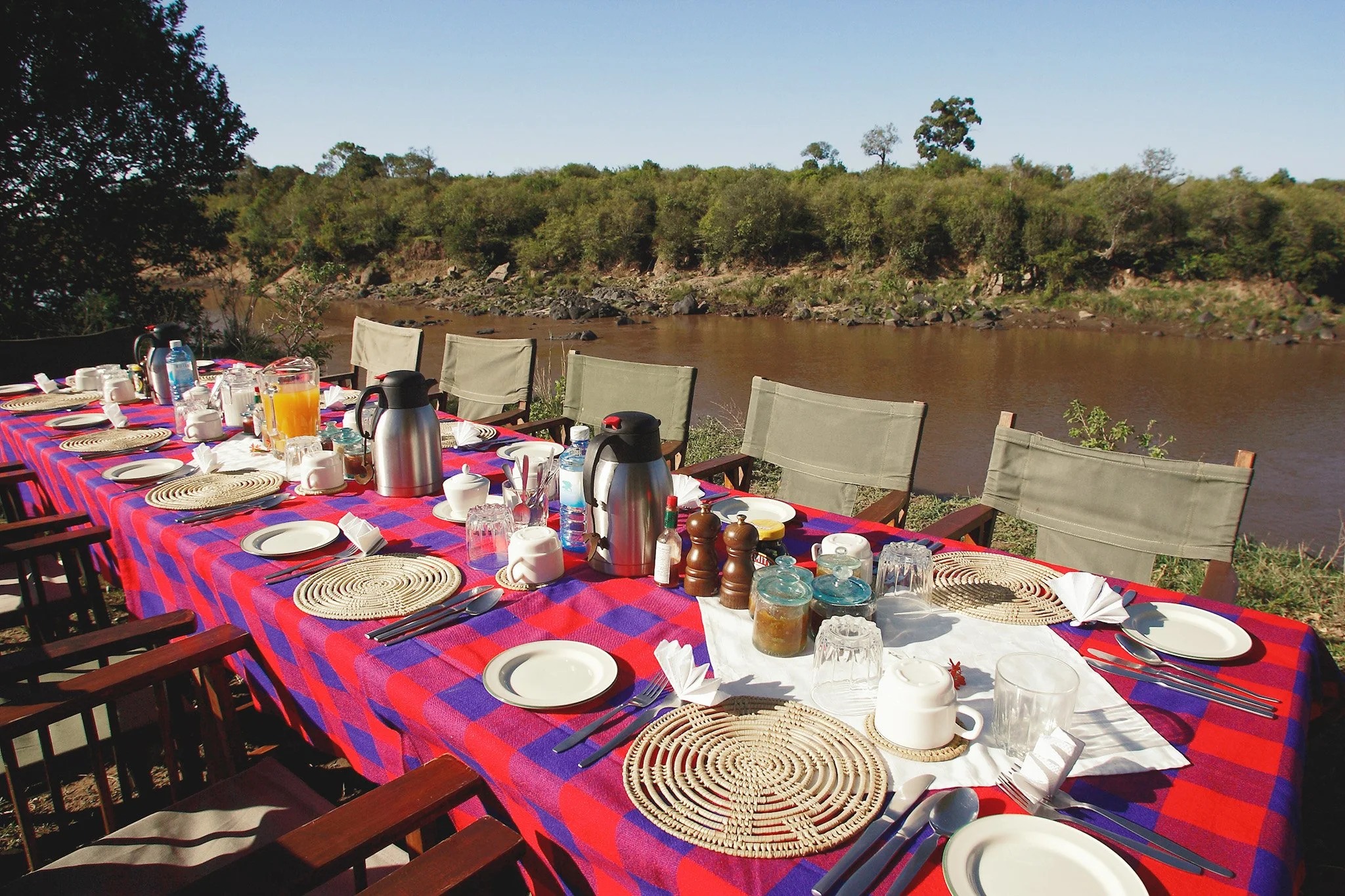 Breakfast laid along the Mara River bank on a Maasai-cloth table at Enkoropil Mara Camp
