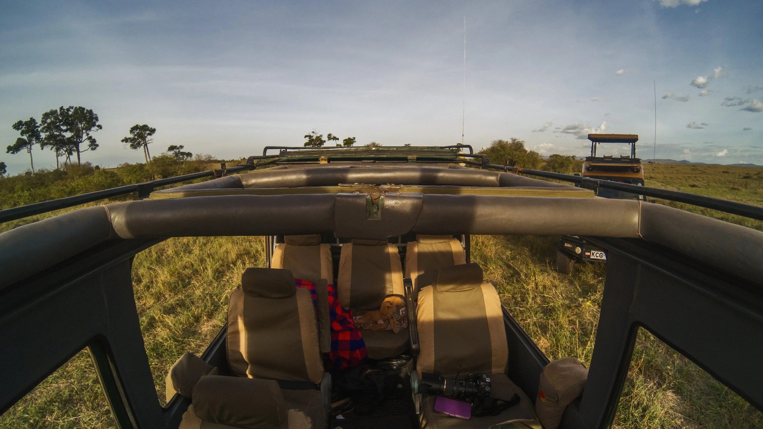 View from inside an open-roof safari vehicle looking out over the Maasai Mara