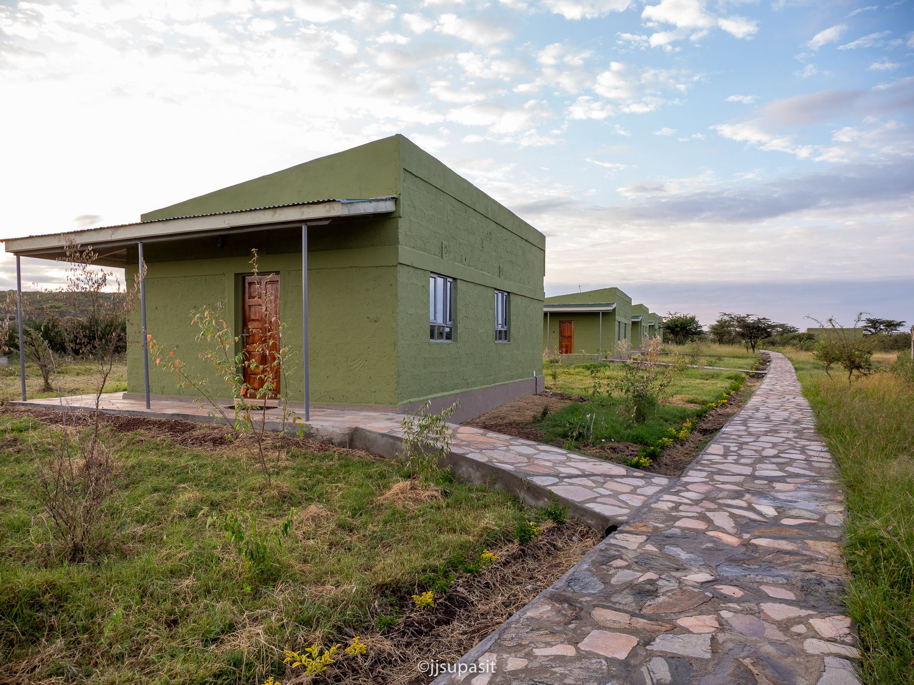 Stone pathway running alongside Enkoropil Mara Camp's ensuite cottage suites at dusk
