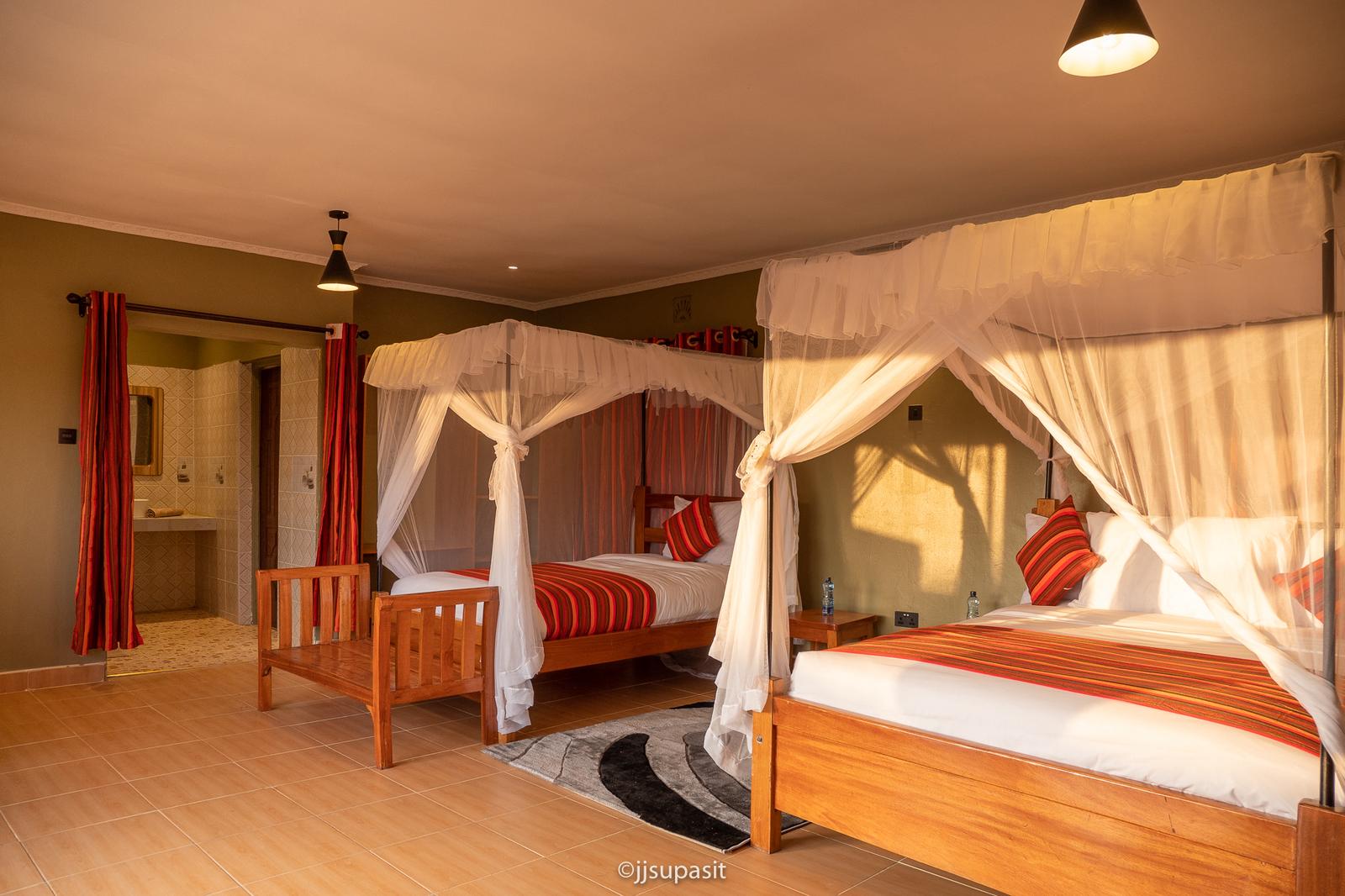 Spacious family suite with two four-poster canopy beds and Maasai-stripe linens